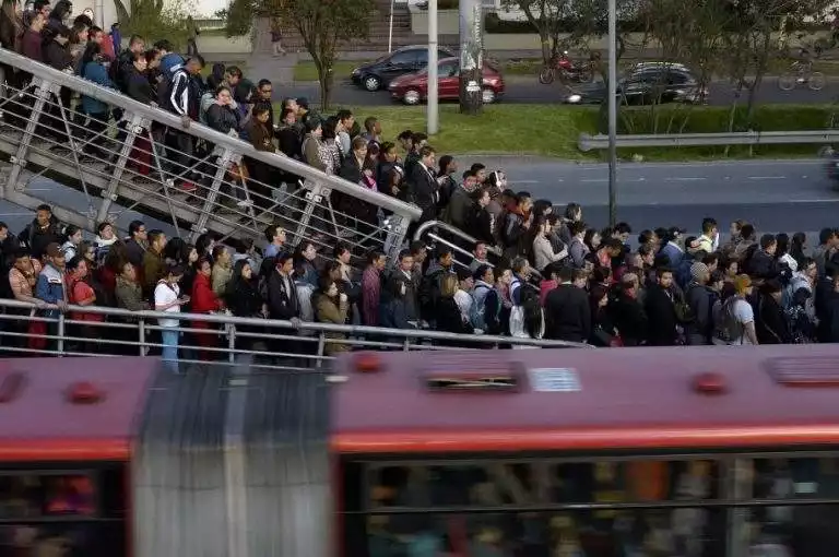 Crowd of people on a bridge to catch a transmilenio.